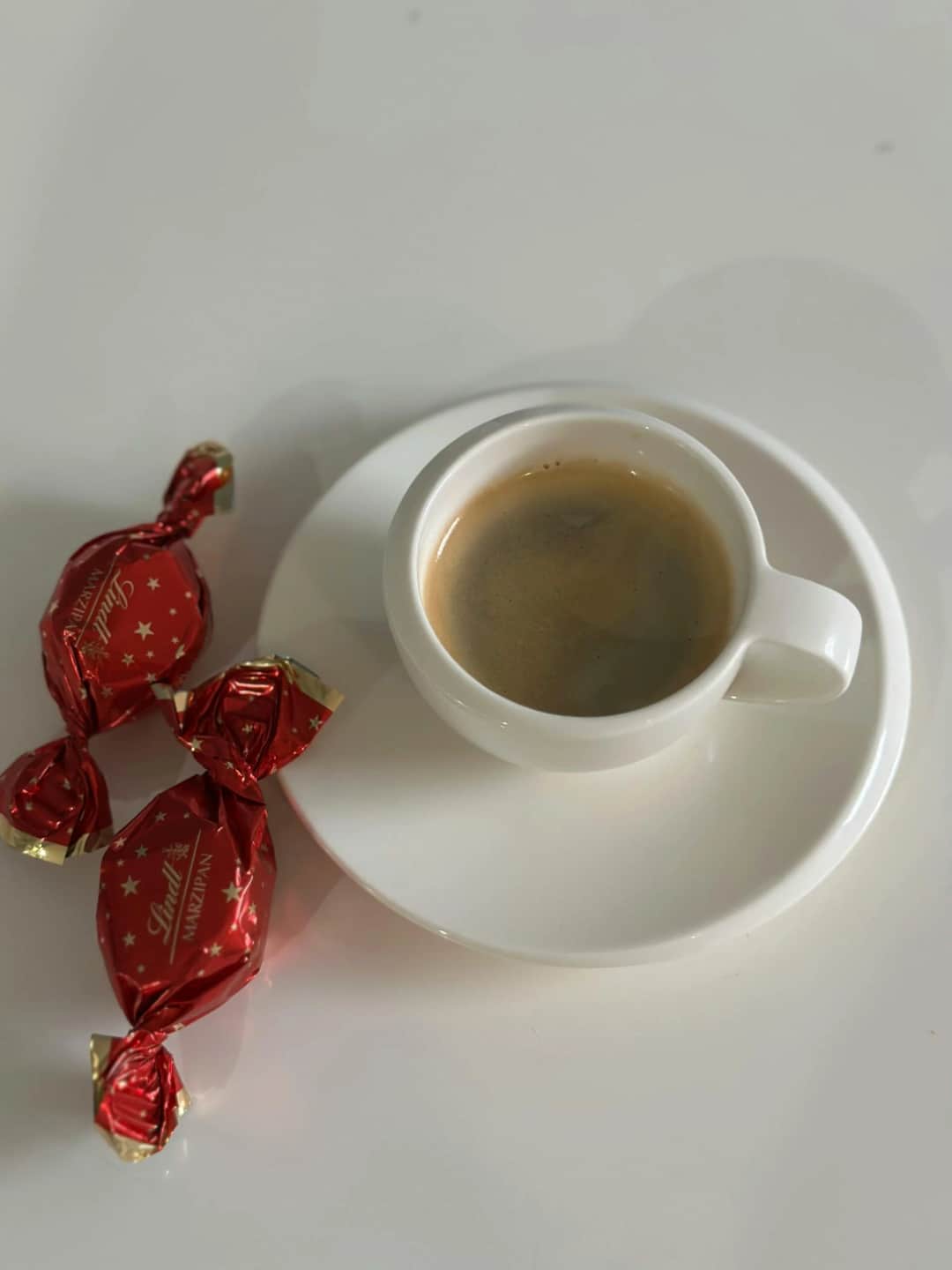 White coffee cup with espresso and Lindt chocolates on table. (Photo: Vadim Malitskii via Pexels)