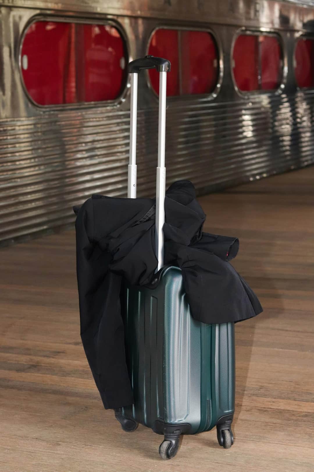A sleek suitcase placed on a railway platform with a jacket draped over its handle. (Photo: Guilherme Simão via Pexels)