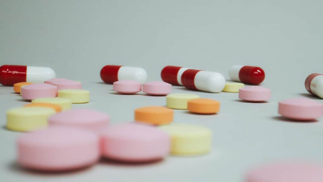 Close-up of varied pills and capsules scattered on a white surface. (Photo: Tima Miroshnichenko via Pexels)