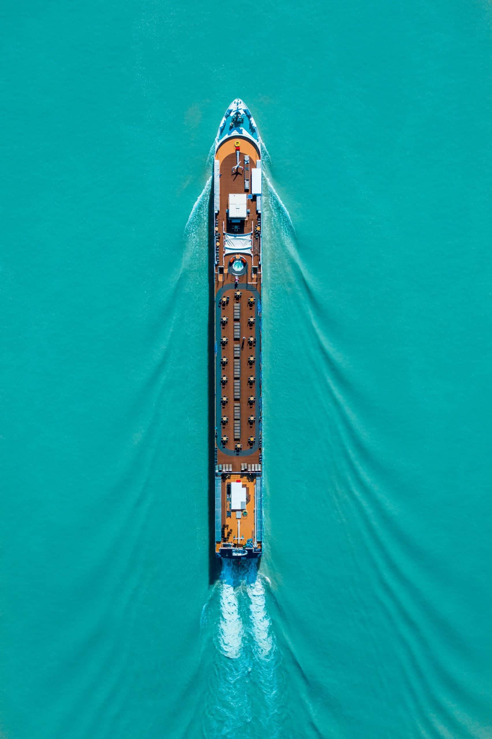 Aerial view of a large cargo ship navigating turquoise waters, showcasing marine transportation.