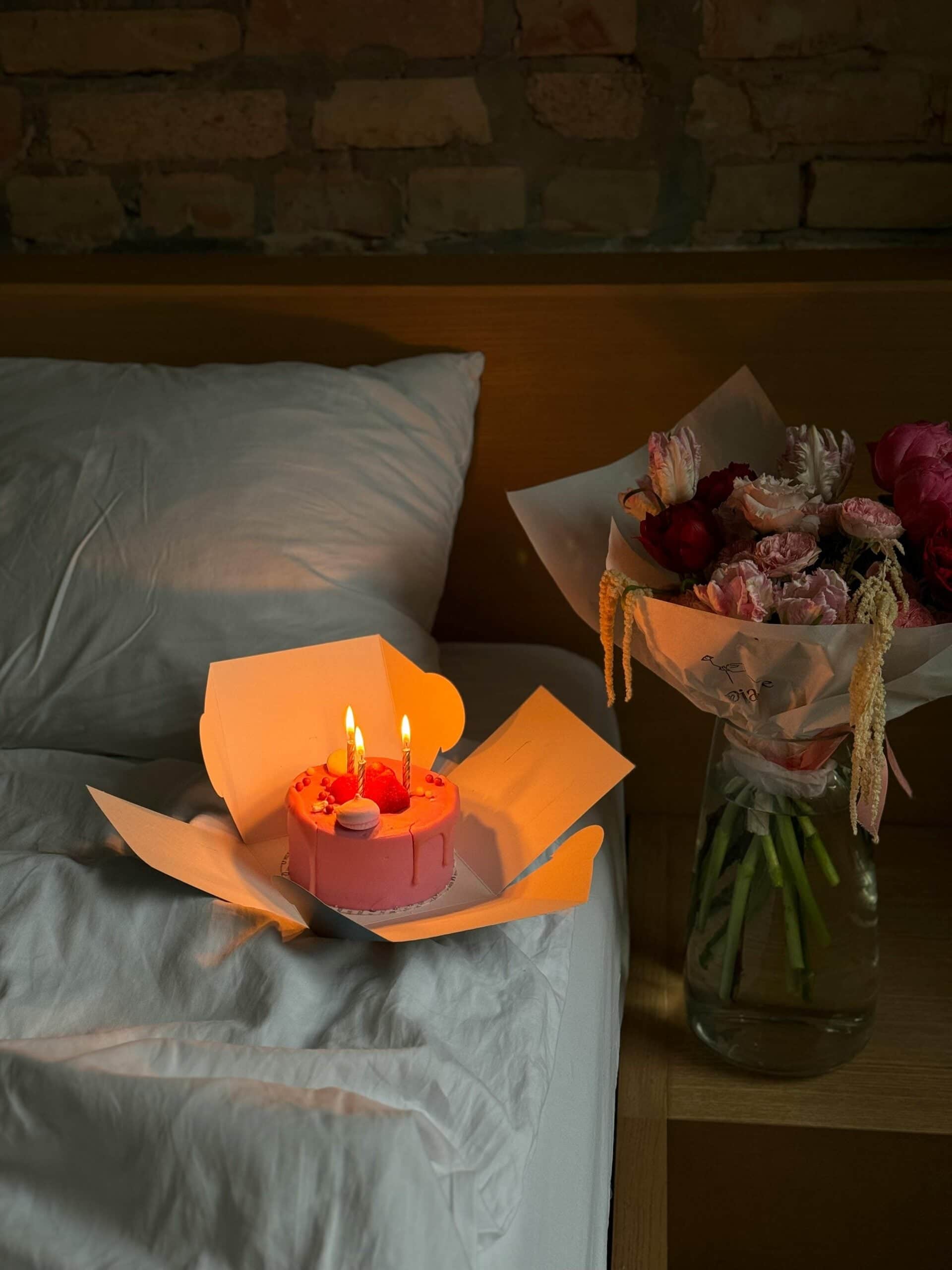 Burning candles and fresh flowers arranged on bed creating warm, relaxing home ambiance