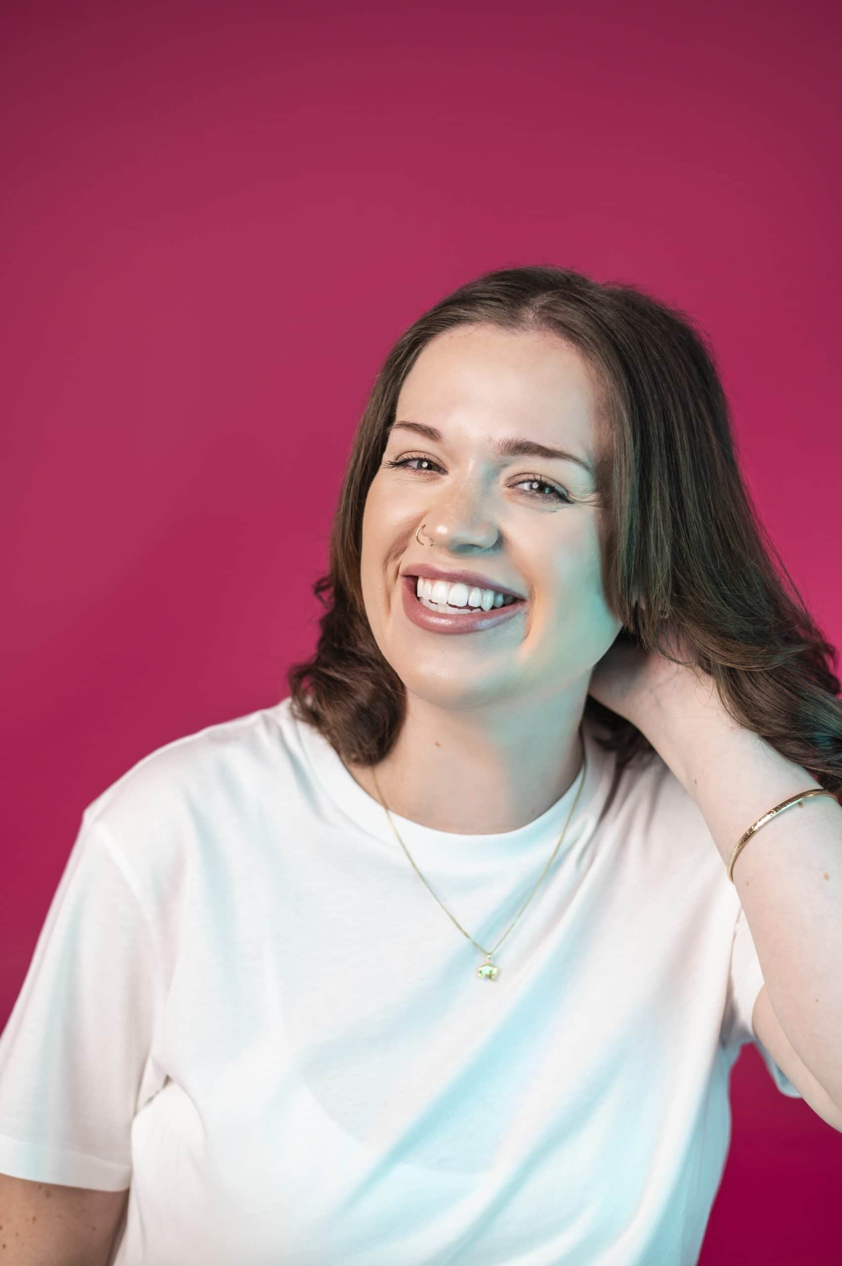 Smiling woman in a white t-shirt with a pink background at Salience marketing agency.