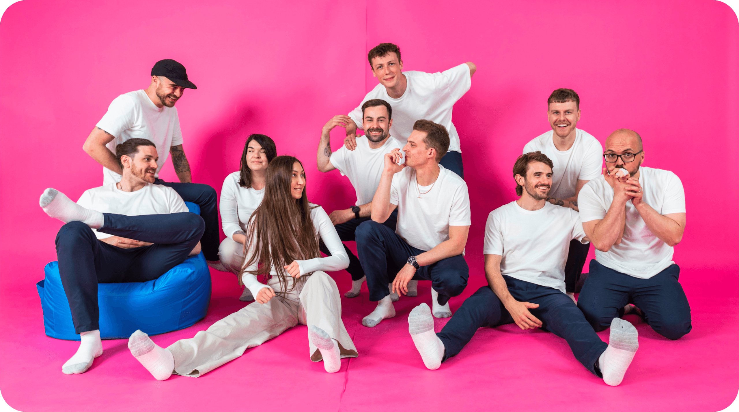 Team members of Salience marketing agency posing in coordinated white outfits against a pink backdrop.