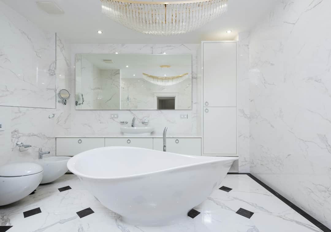 Interior of clean contemporary white bathroom with sparkling chandelier above soaking tub in light (Photo: Max Vakhtbovych via Pexels)