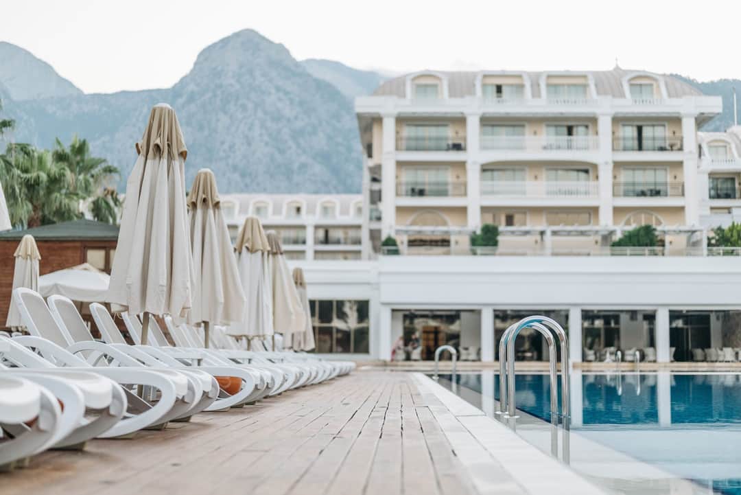 Empty sunloungers and umbrellas by a luxury resort pool with a mountain view. (Photo: Pavel Danilyuk via Pexels)