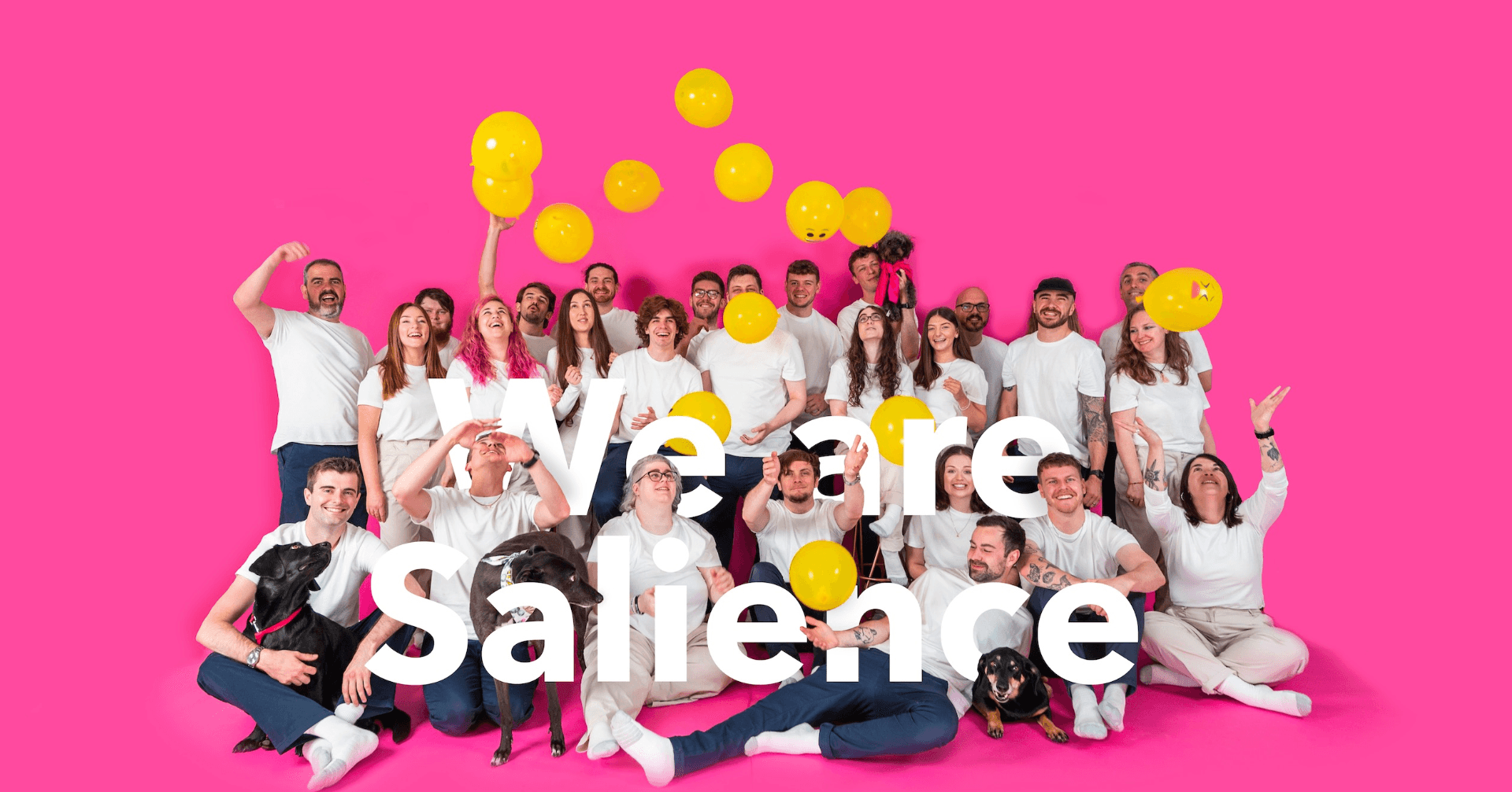 Salience team celebrating with yellow balloons against pink background, reflecting dynamic company culture