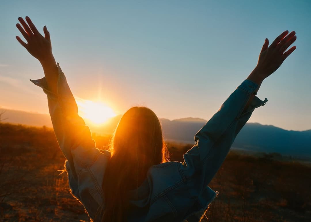 Person celebrating victory with arms raised at sunset symbolizing ecommerce success