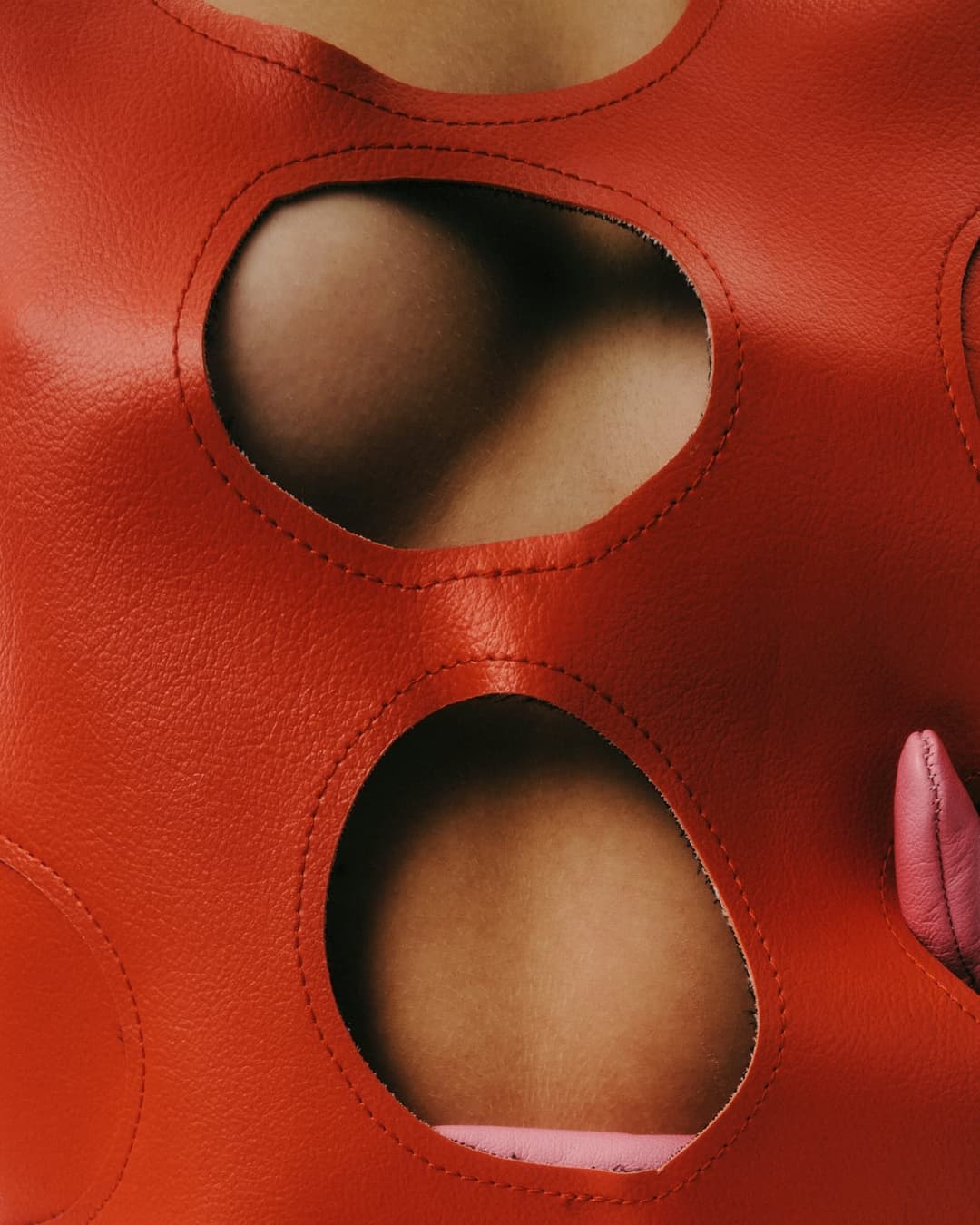 Red intimate apparel with oval cutouts revealing skin tones in sexual wellness product photography