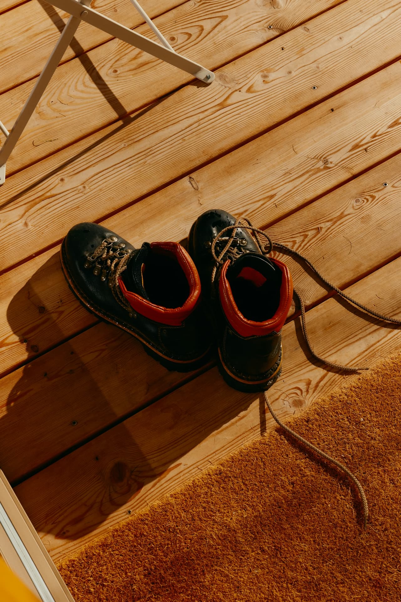 Worn hiking boots on wooden deck, showcasing outdoor adventure readiness.