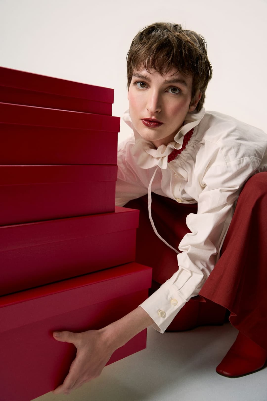 Woman posed with stacked red products symbolizing high SKU complexity and inventory control