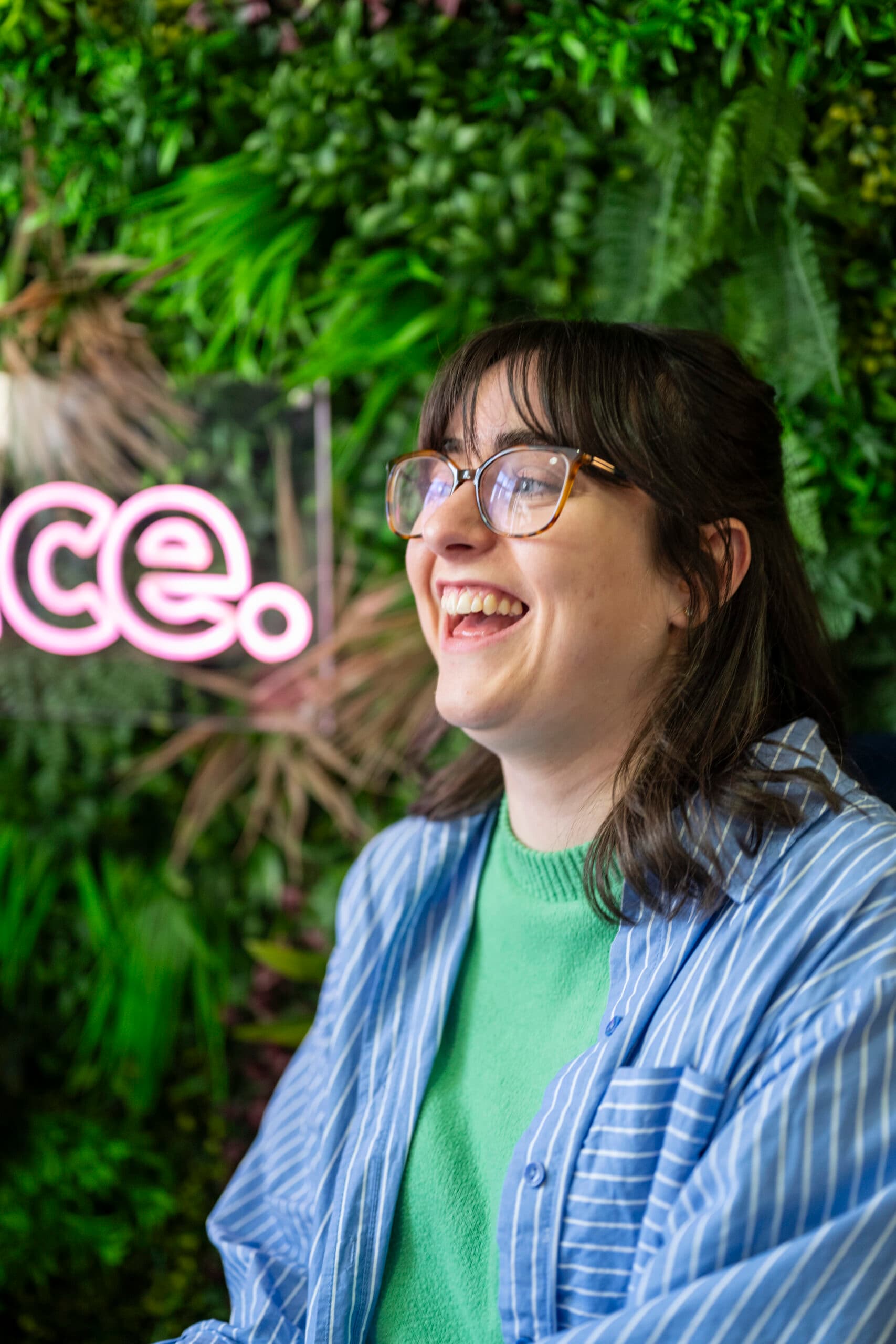 Smiling individual in glasses with greenery background at Salience marketing agency.