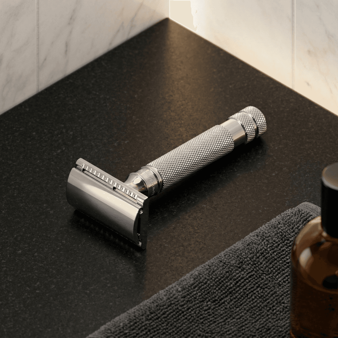 Safety razor with chrome finish and textured grip on black grooming mat