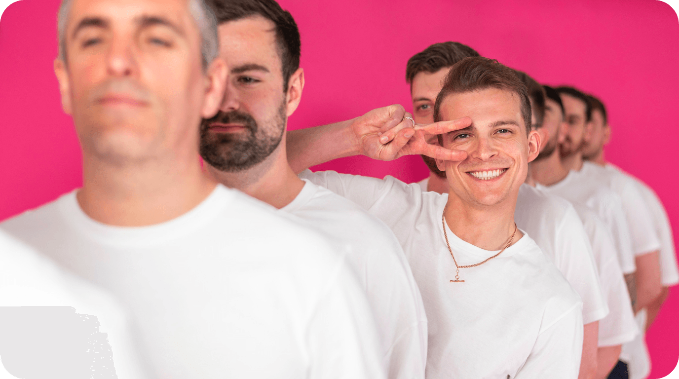 Men in white shirts lined up against a pink background, showcasing team unity at a search marketing agency.