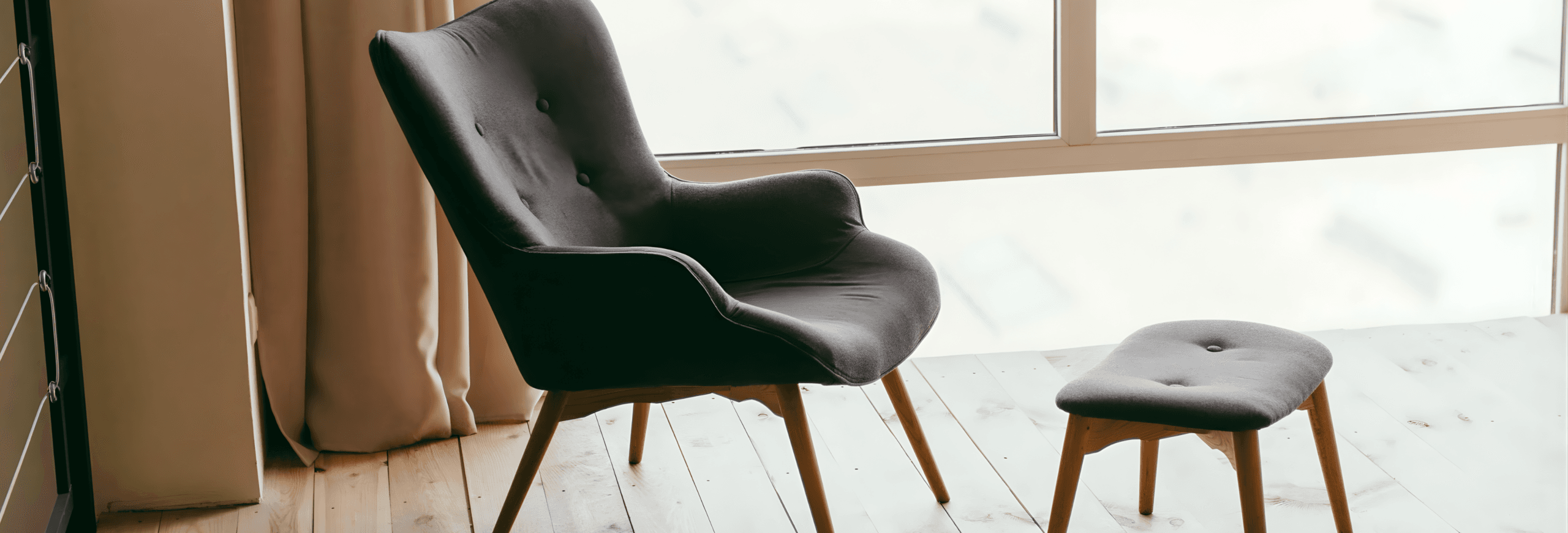 Modern black leather armchair with wooden legs and ottoman in contemporary interior case study