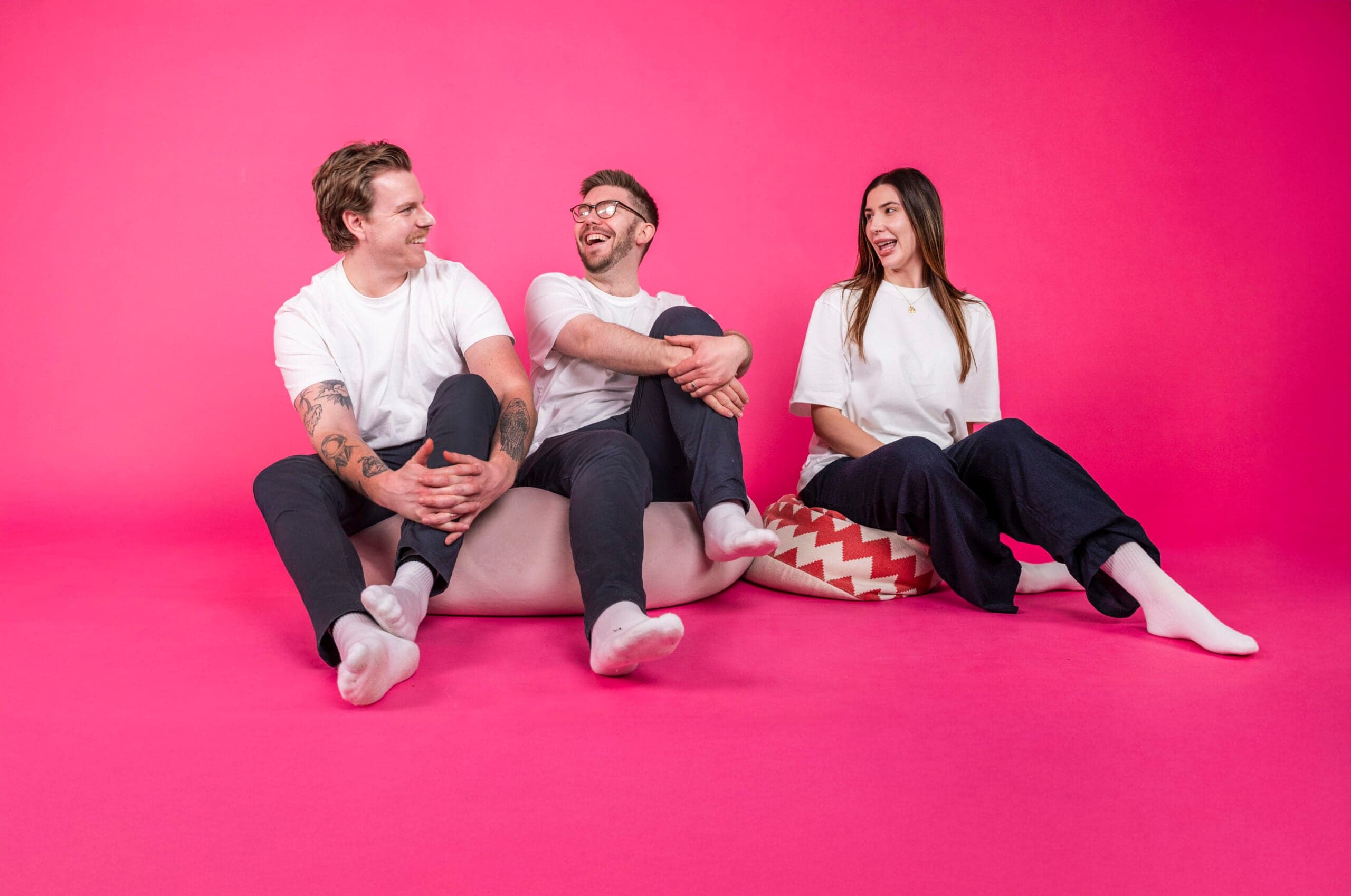E-commerce marketing team of three against vibrant pink background