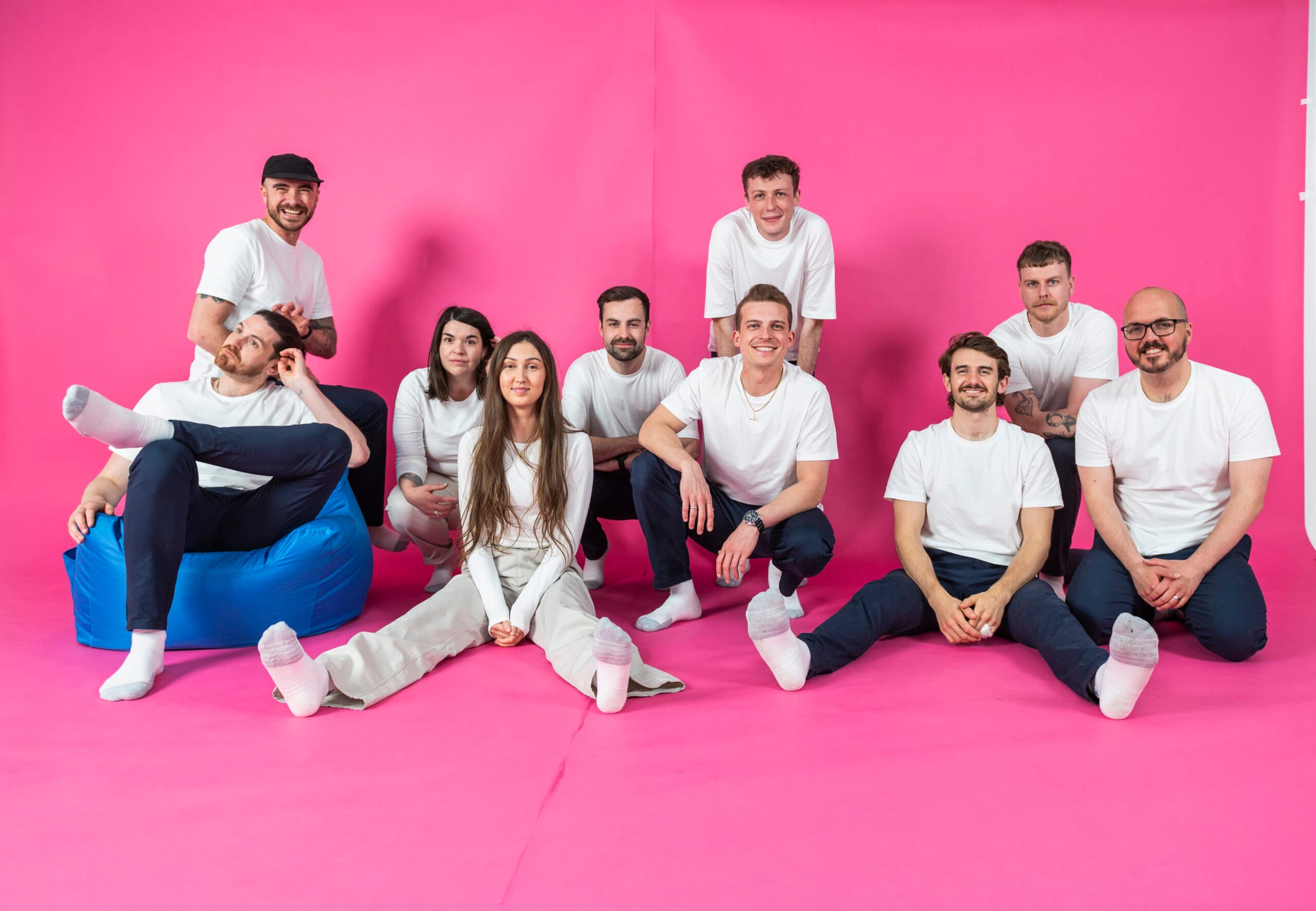 Team members of Salience marketing agency posing on a pink background in casual attire.