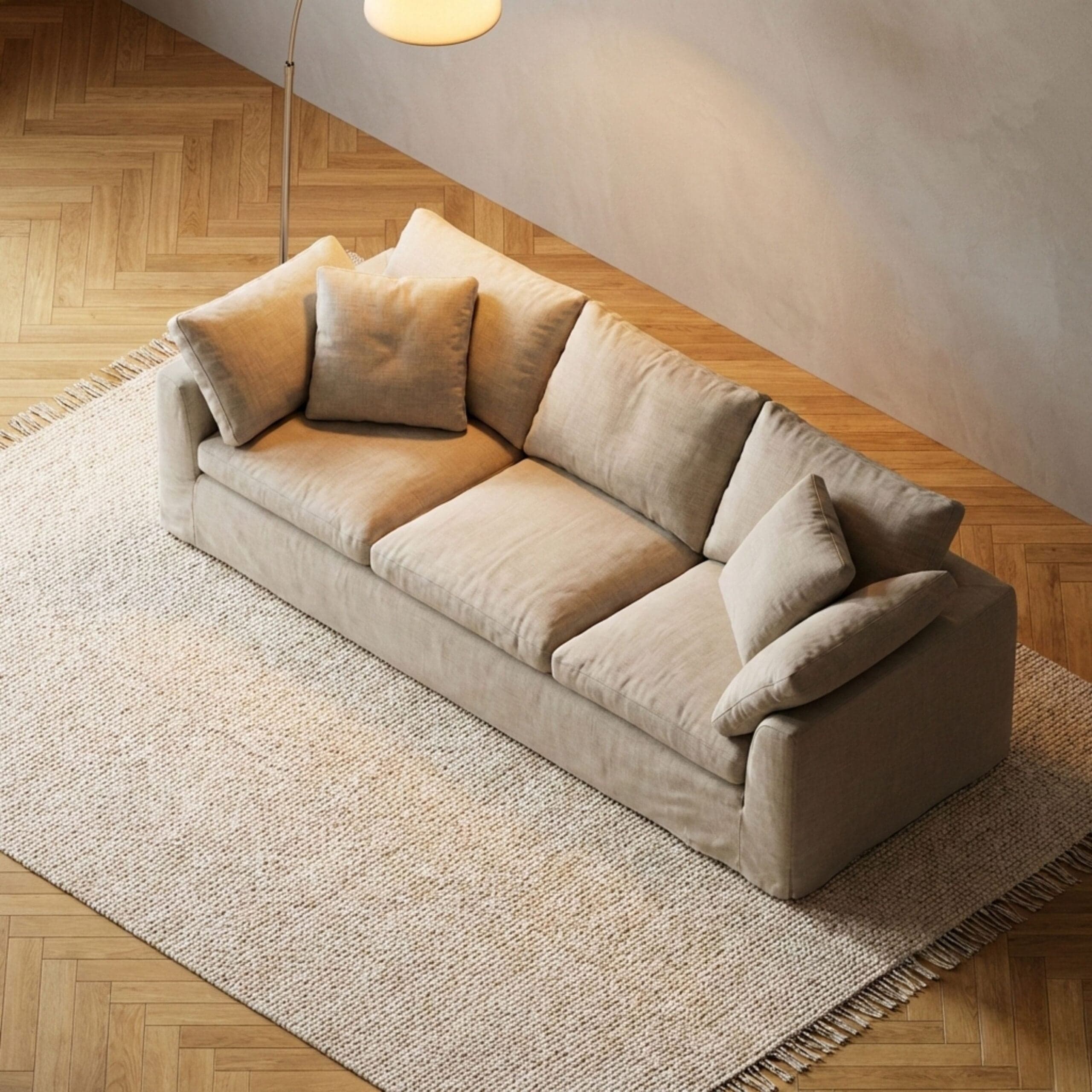 Beige sofa with cushions on a woven rug, wooden floor, modern living room ambiance.