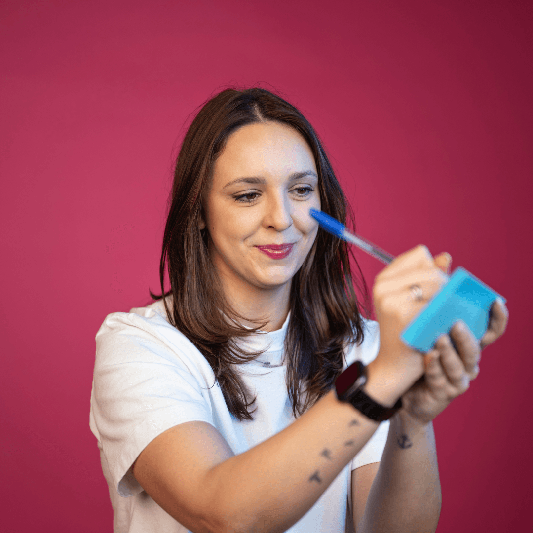 Marketing professional demonstrating design tools and product packaging on pink background