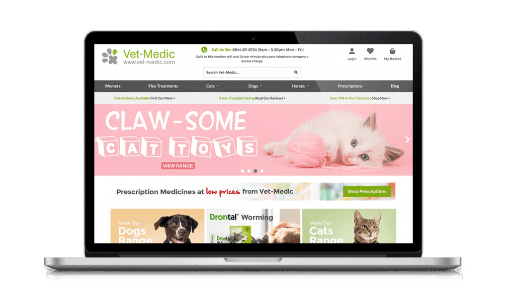 Laptop displaying Vet-Medic website featuring cat toys with image of a playful kitten and product categories.