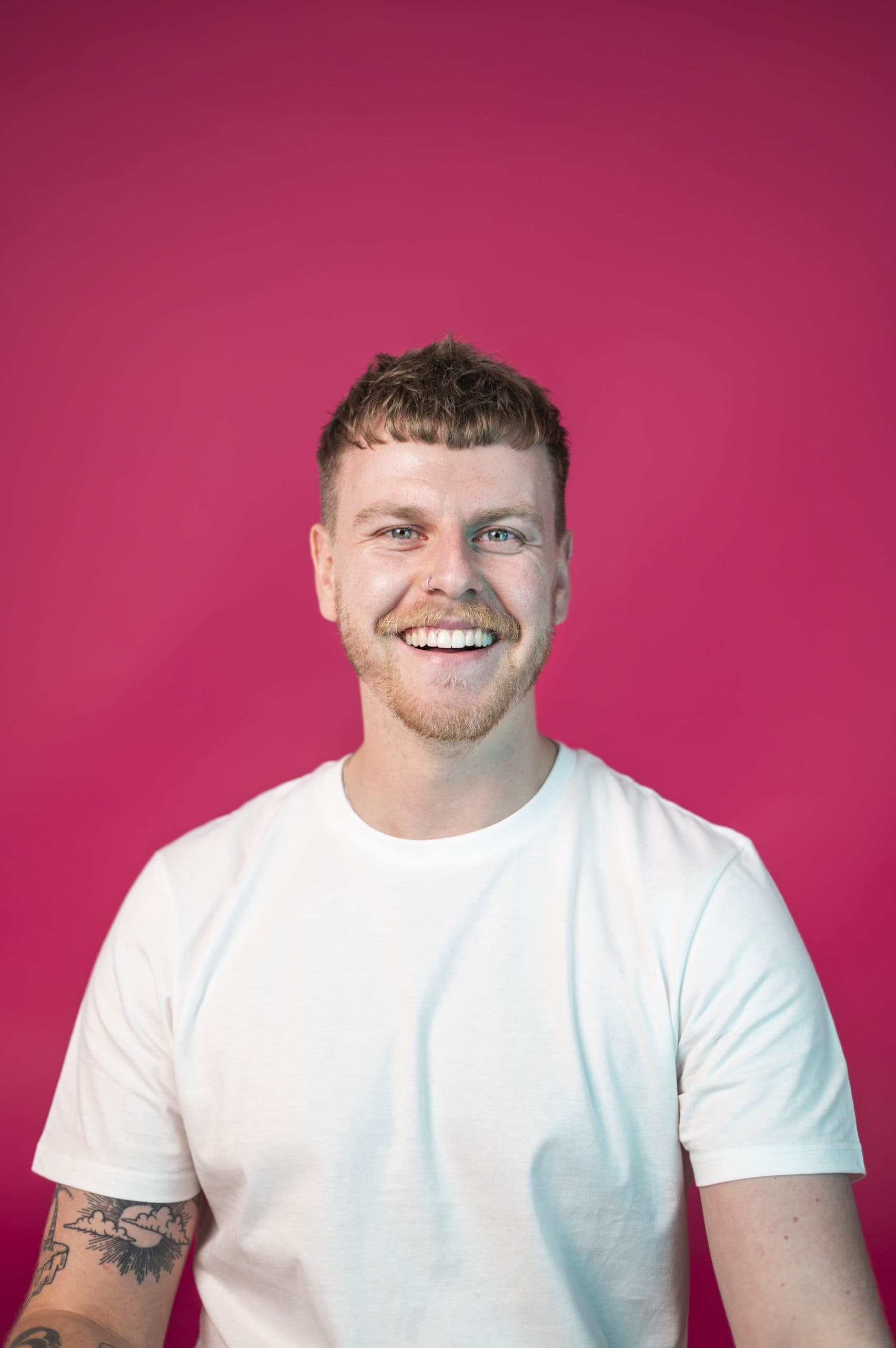 Smiling man in a white t-shirt against a vibrant pink background at Salience marketing agency.