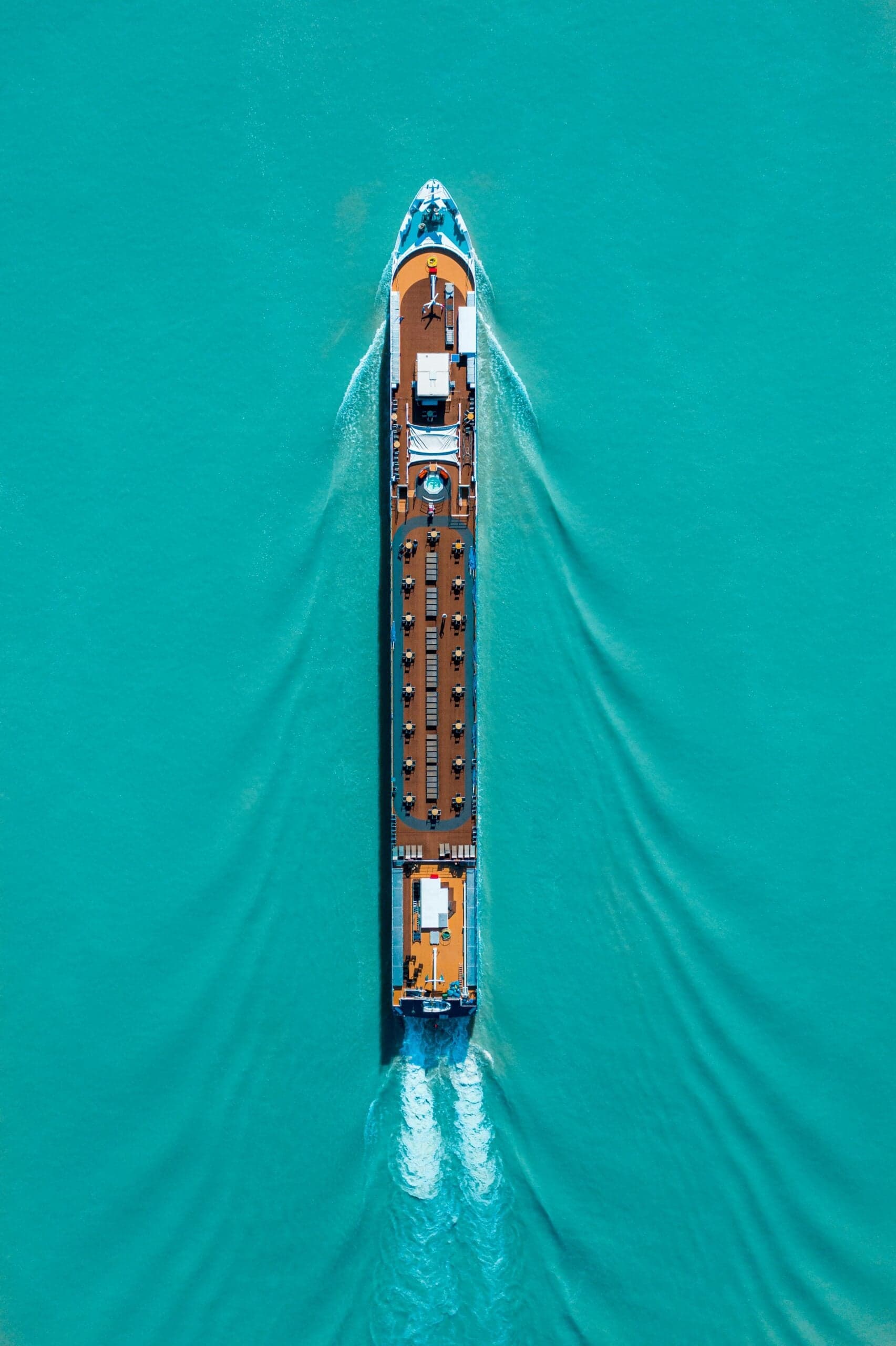 Aerial view of a large cargo ship navigating turquoise waters, showcasing marine transportation.