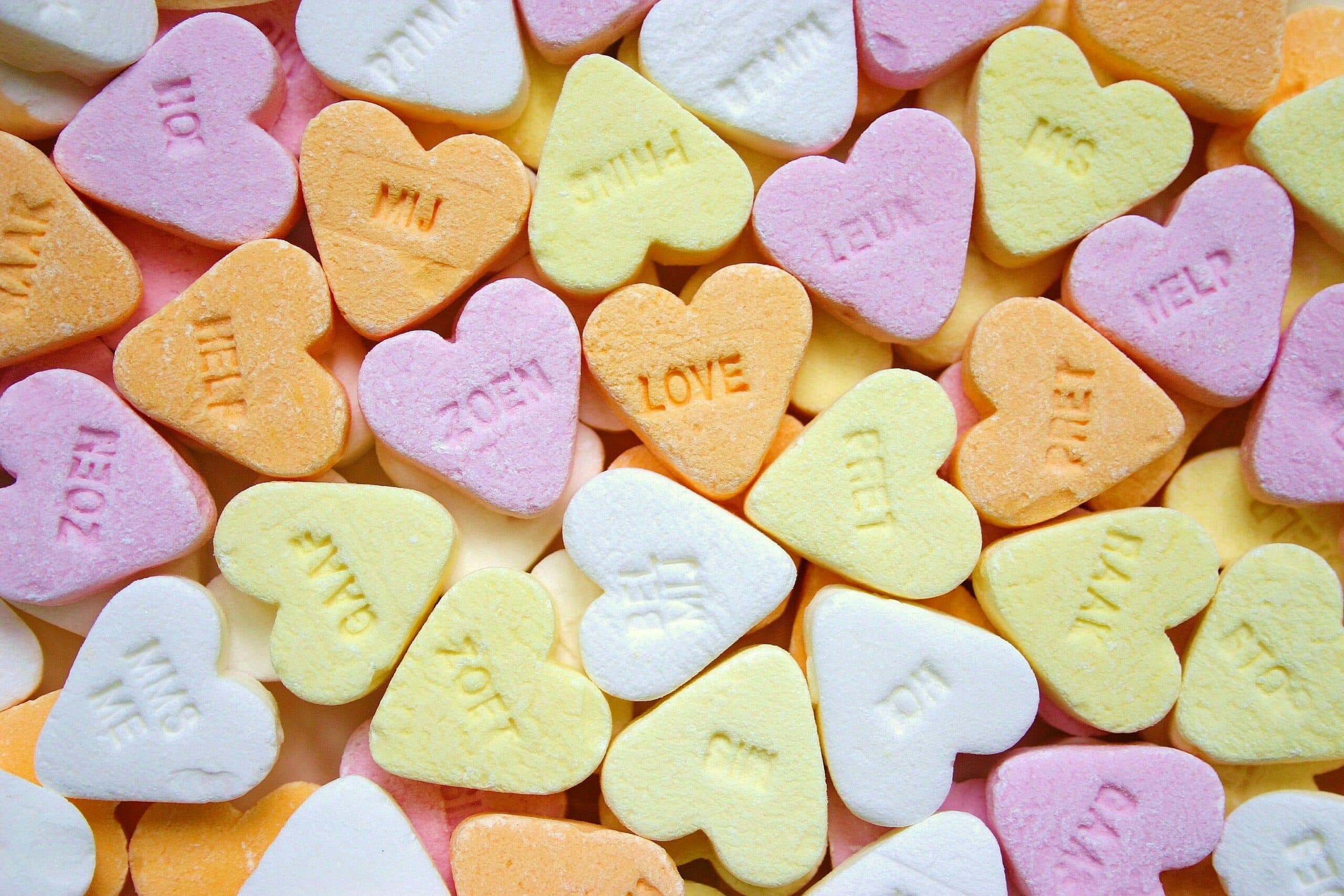 Heart-shaped candy with sweet messages in various pastel colors.