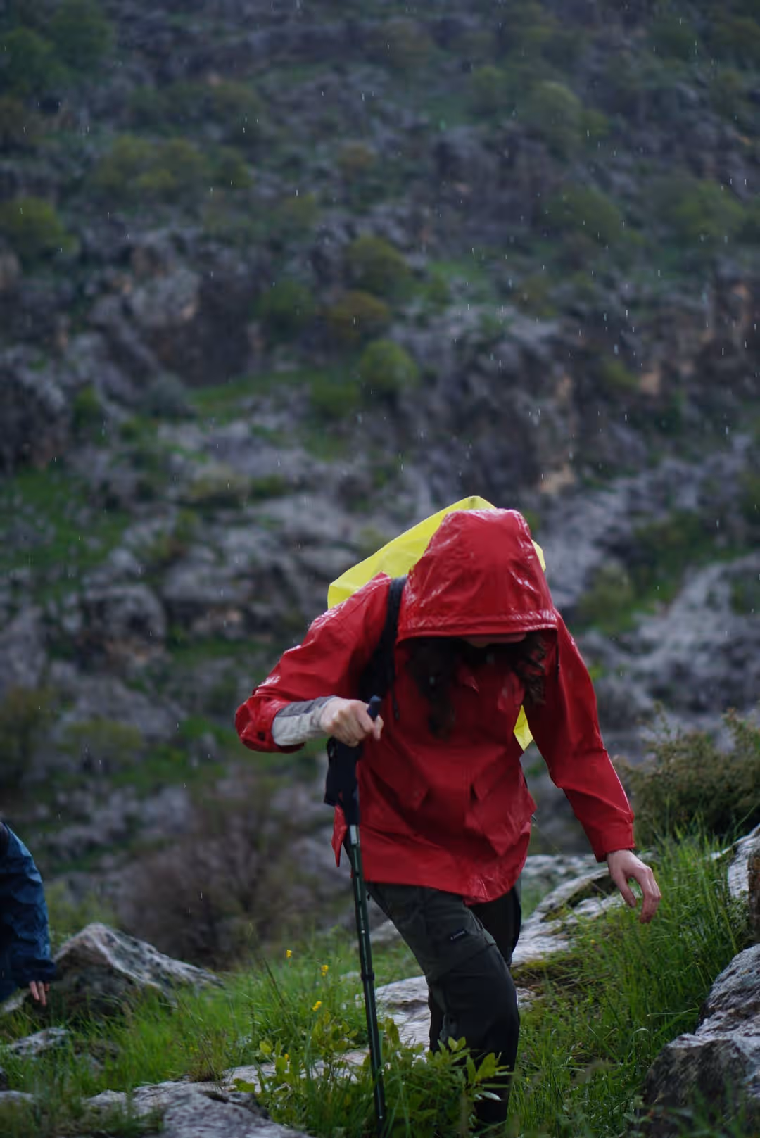 Hiker in red raincoat climbing a rocky mountain path during a rainstorm. (Photo: Hasan Hüseyin TURAN via Pexels)