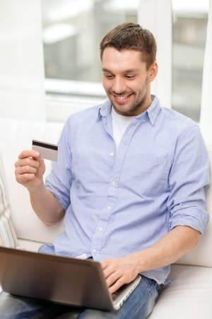 Man smiling and holding a credit card with a laptop in his lap